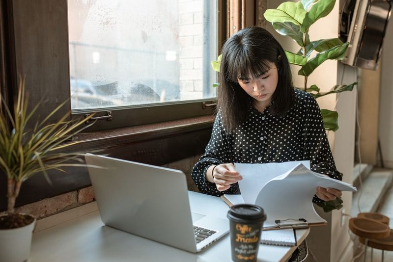 young vietnamese female entrepreneur looking worried laptop documents cafe